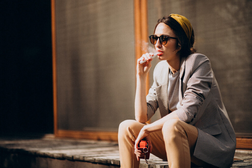 young woman sitting smoking ecigarette