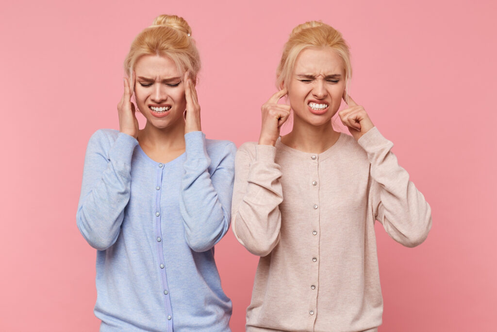 beautiful young blonde twins experience discomfort pain temples tinnitus isolated pink background