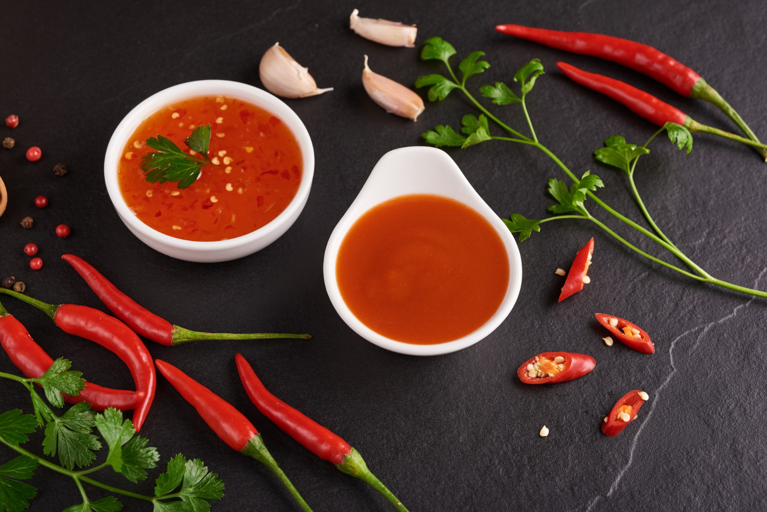 red hot chilli sauce tomato ketchup chilli sauce puree with chili pepper vegetables tomatoes garlic black stone surface top view